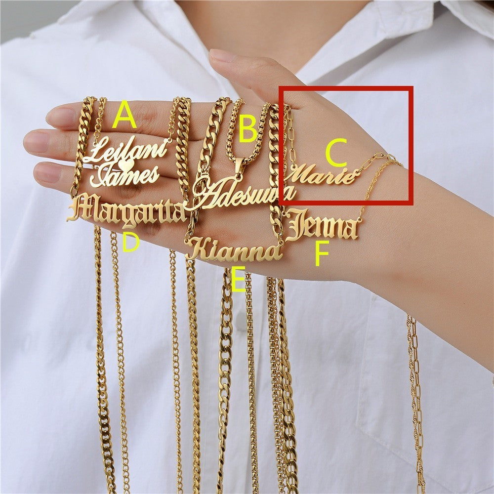 Gold personalised name necklaces held by a person against a white background