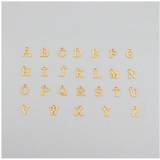 Gold alphabet letters for a necklace on a light grey background