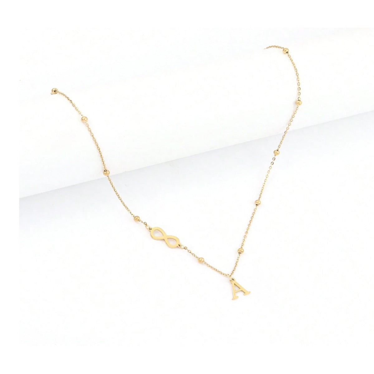 Gold necklace with a personalised initial infinity symbol on a white background