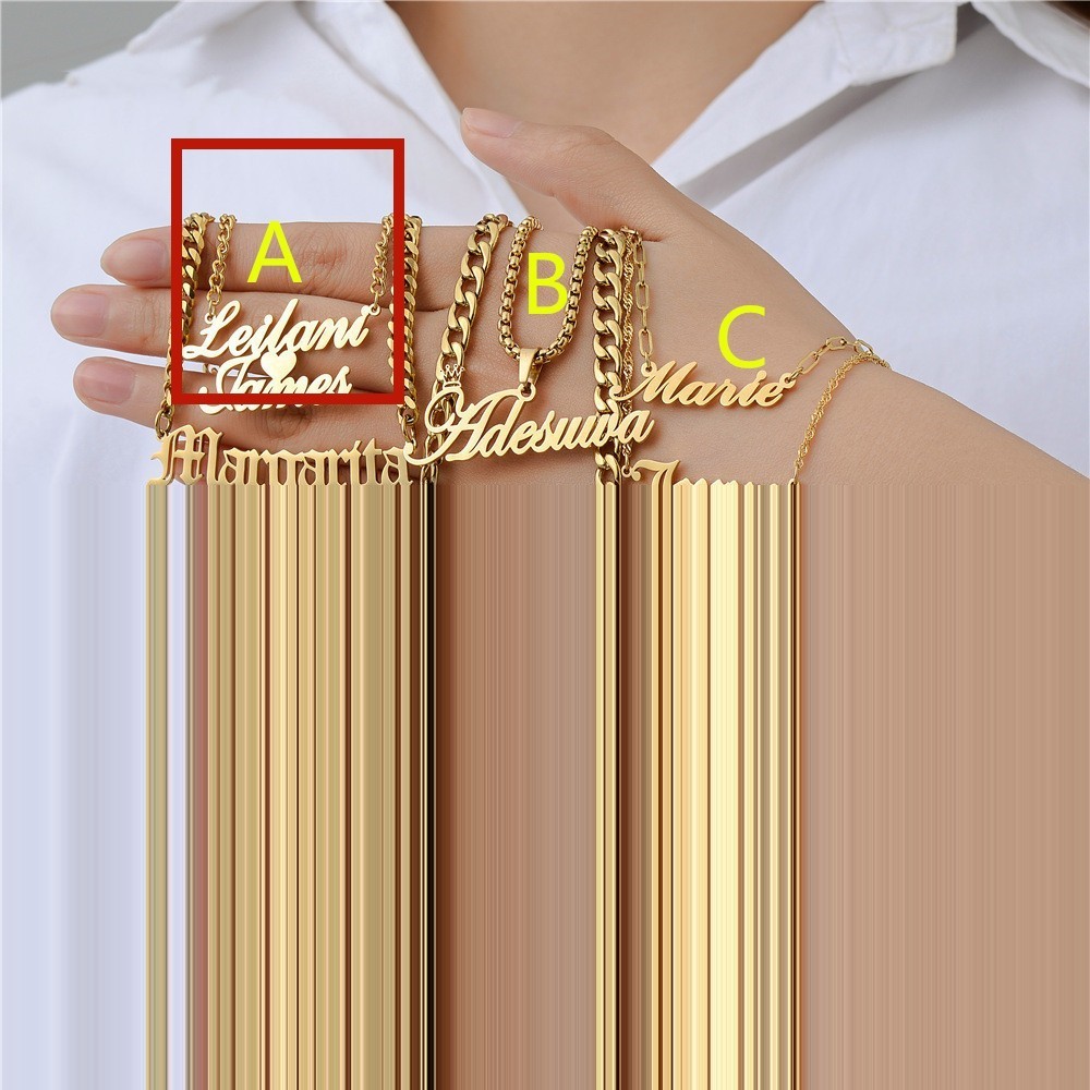 Three gold personalised necklaces with names on them held by a person wearing a white shirt.