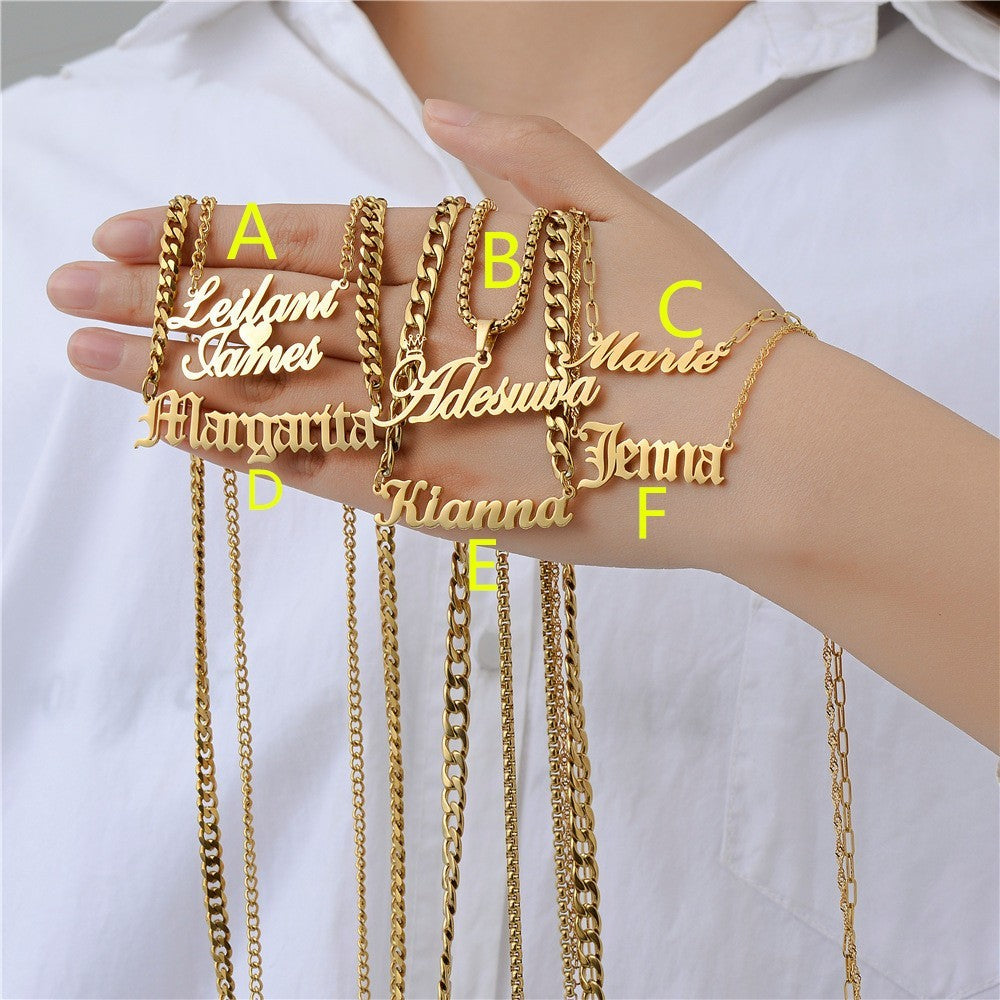 Gold personalised necklaces held by a person against a white background